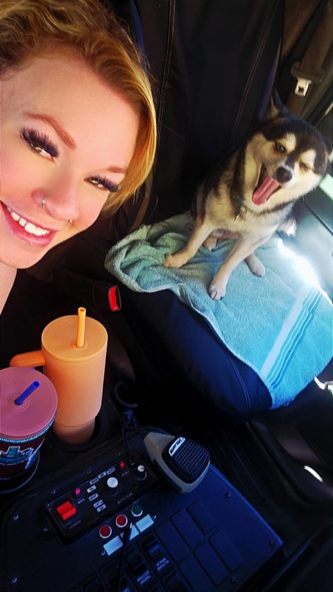 Amanda smiling beside a husky resting on a towel